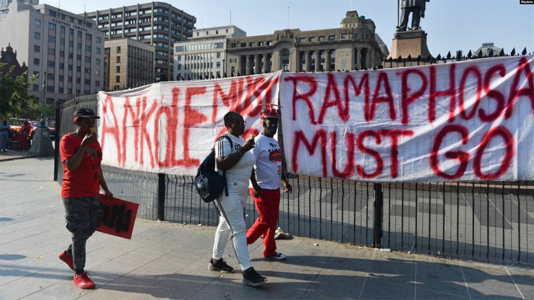 south-africans-walk-past-protestors-banner