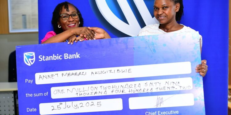 Sarah Nankumba, the Stanbic Acacia branch manager handing over a dummy cheque to Akugizibwe Annet Mbabazi, One of the lucky winners in the kyadouble with Supa Dupa campaign