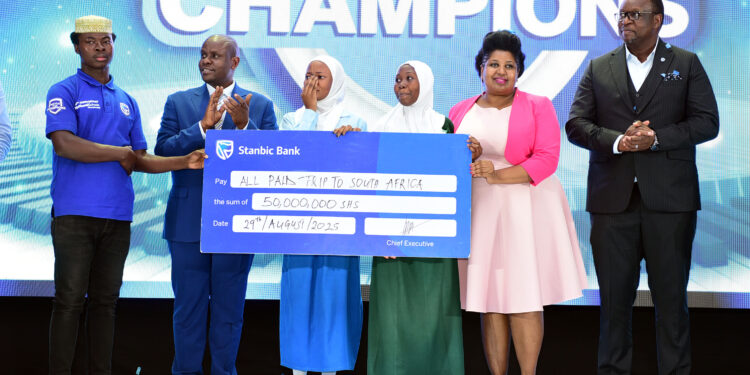 Mumba Kalifungwa (R) Stanbic Bank Chief Executive together with Minister Balaam Barugahara and PSFU's Sarah Kagingo handing over the travel dummie cheque to Sumaya Girls students